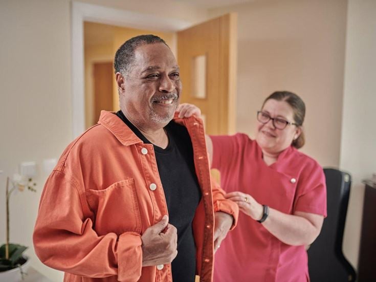 McCarthy & Stone care staff helping man put on jacket