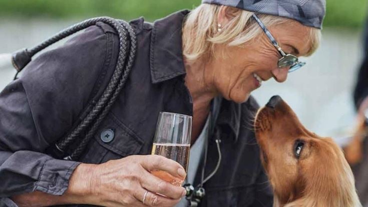 a man holding a glass of wine and a dog