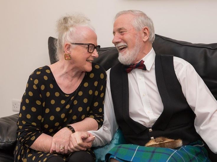 Jessie and Hugh laughing on the couch