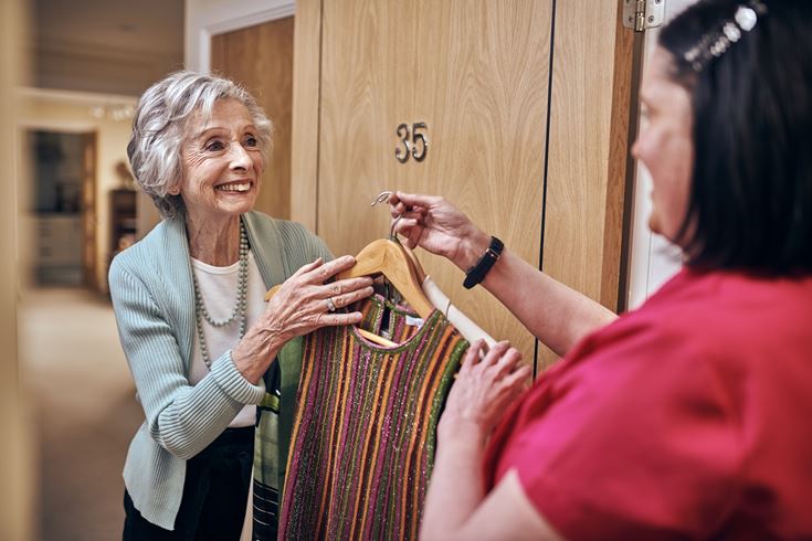 An older woman in a McCarthy & Stone retirement flat being handed clean laundry.