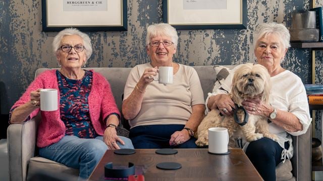 a group of women sitting on a couch with a dog