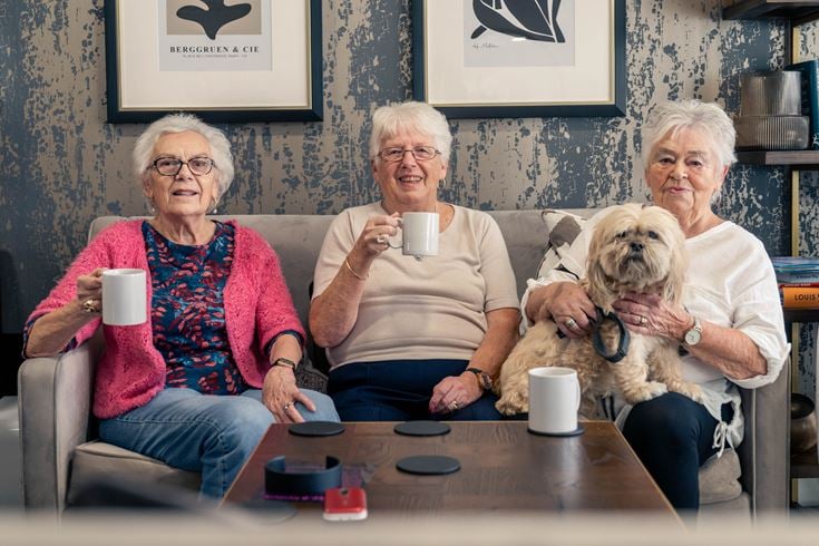 a group of women sitting on a couch with a dog