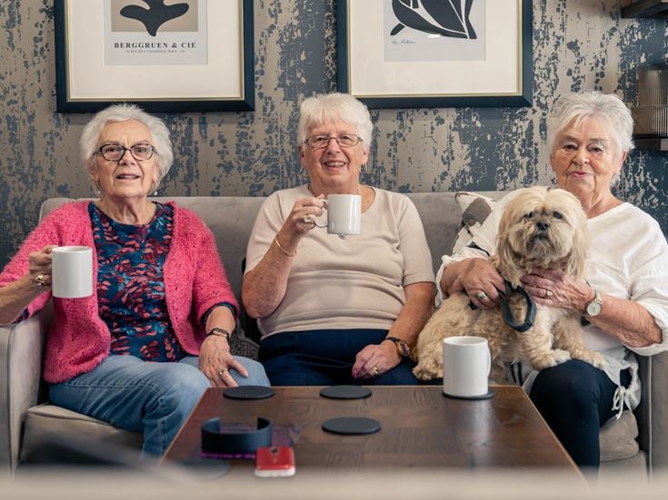 a group of women sitting on a couch with a dog