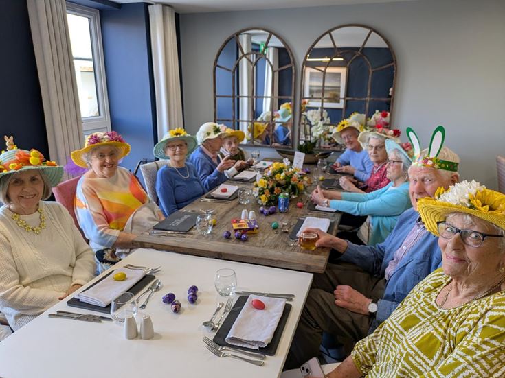 a group of people sitting at a table wearing hats