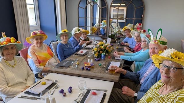 a group of people sitting at a table wearing hats