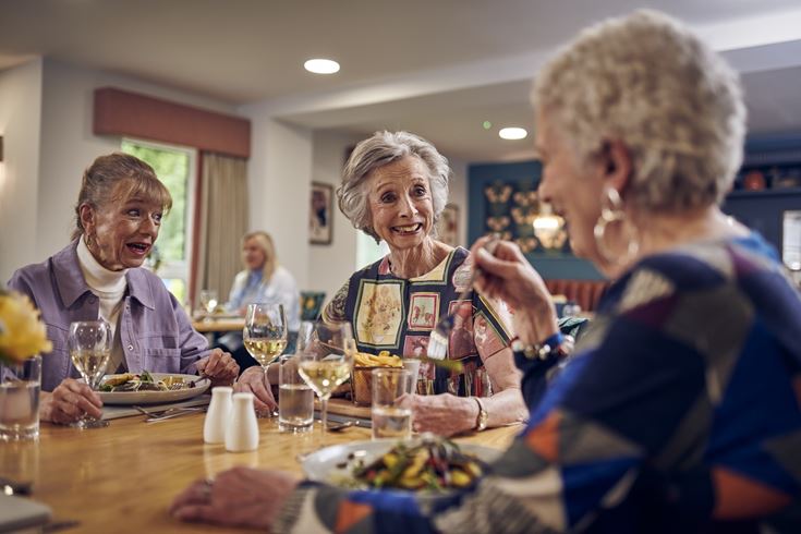 A group of retired women at a table enjoying a meal in a retirement home