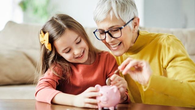 Grandmother and granddaughter counting money and adding it to a piggy bank, representing saving strategies for retirement