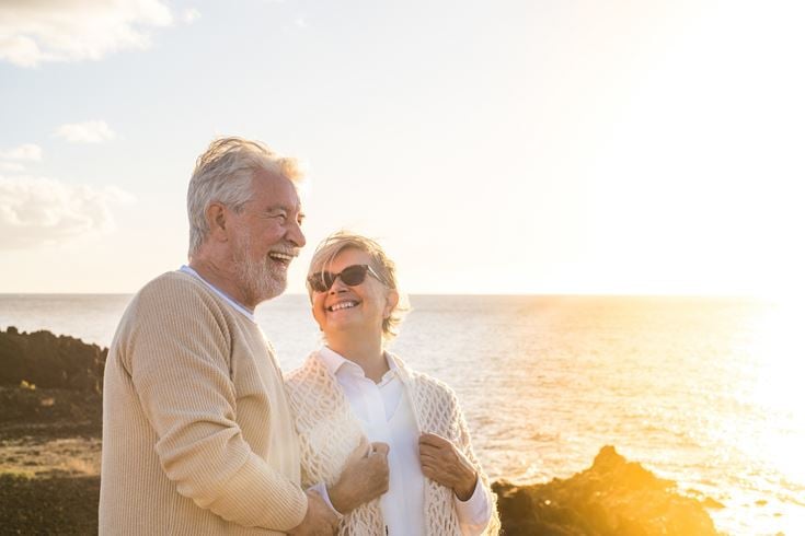 a man and woman posing for a picture by the water
