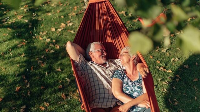 a man and woman sitting in a hammock in a yard
