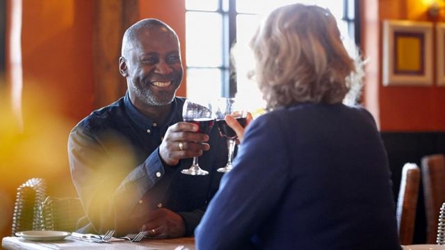 a man and a woman sitting at a table with wine glasses