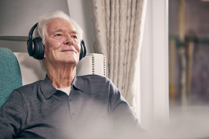 An older man relaxing and listening to music in a retirement home showing how to unwind and improve sleep quality.
