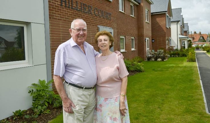 a man and woman standing in front of a brick building