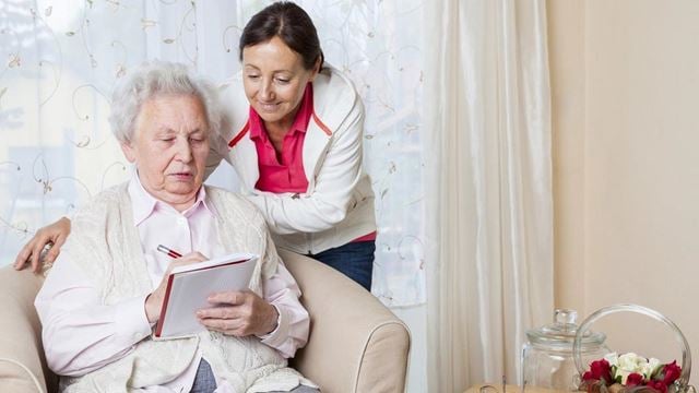 a man and woman sitting on a couch looking at a book