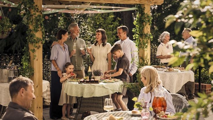 A group of people standing around a table with food on it.