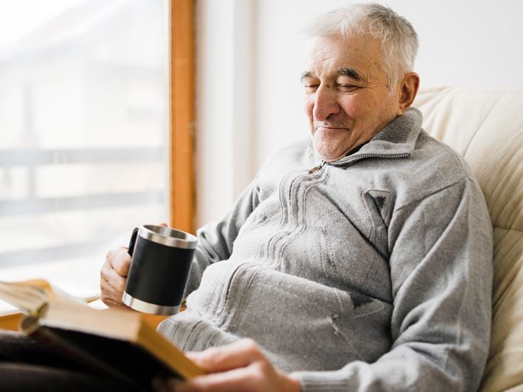 a man sitting on a couch and reading a book