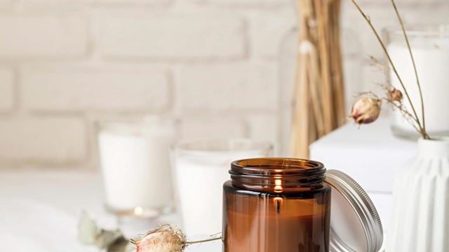 A cream-coloured, homemade candle in a small jar with a lid