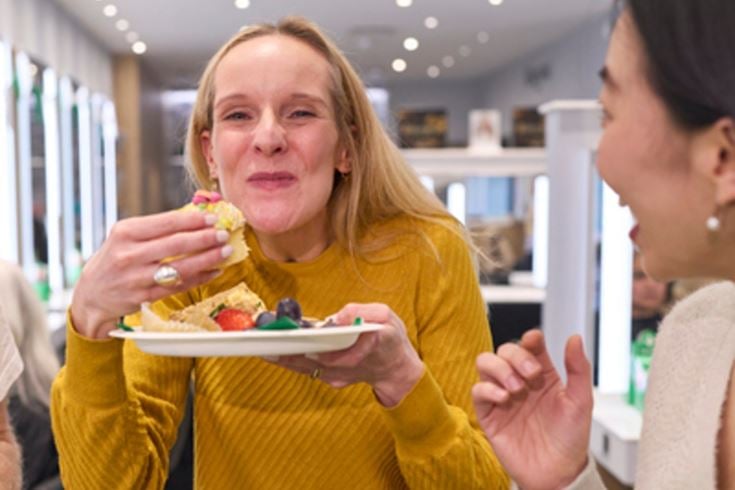 Two people enjoying cakes and snacks at a Macmillan coffee morning.