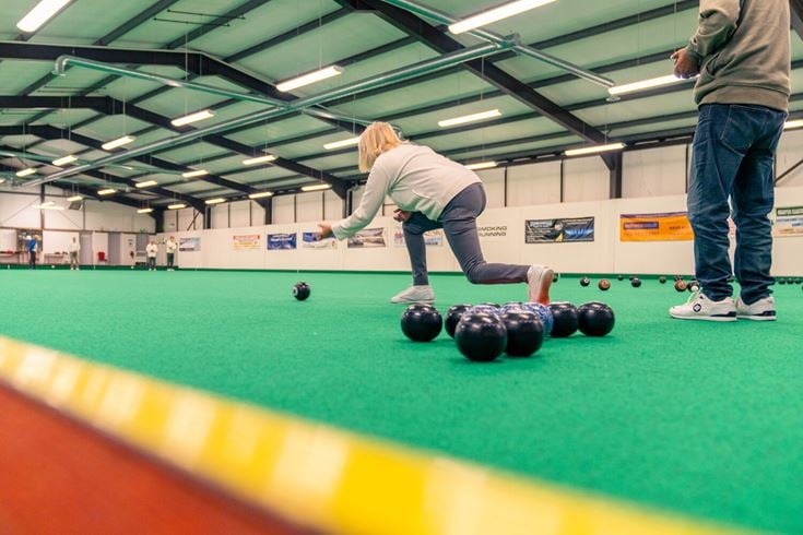 Retired people compete in a game of bowls.