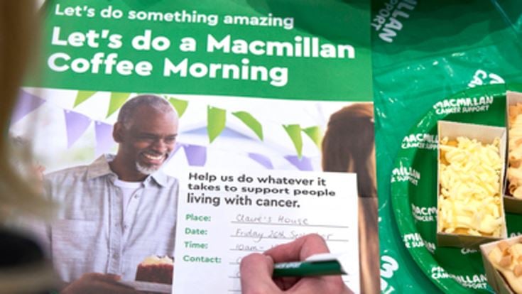 A person fills in a Macmillan coffee morning invitation.