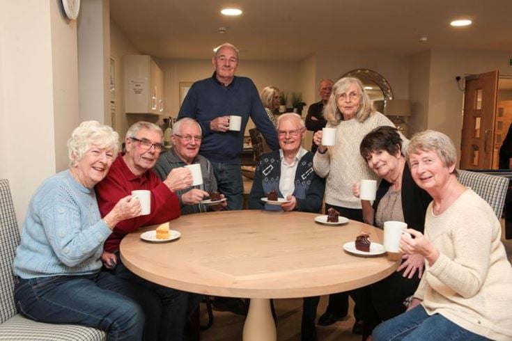 A group of retirees socialising over coffee and cake in a retirement development.