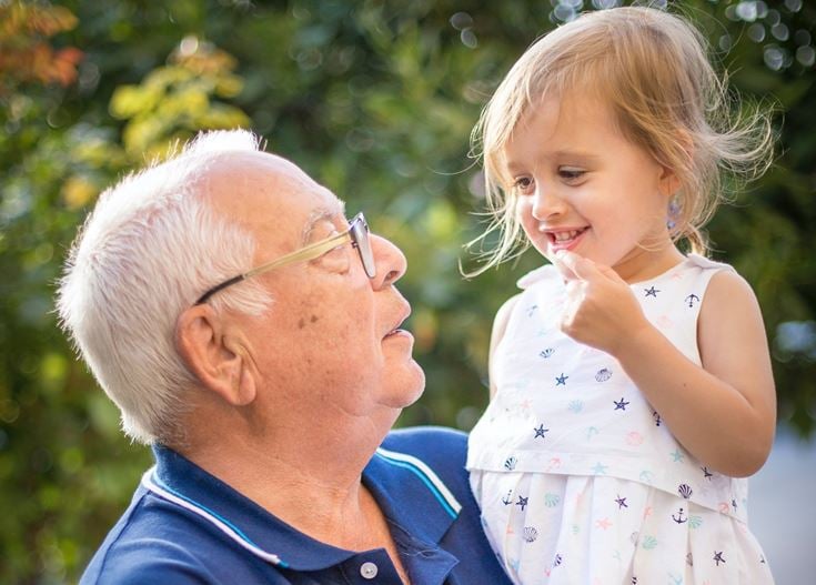 A grandfather holding his smiling granddaughter