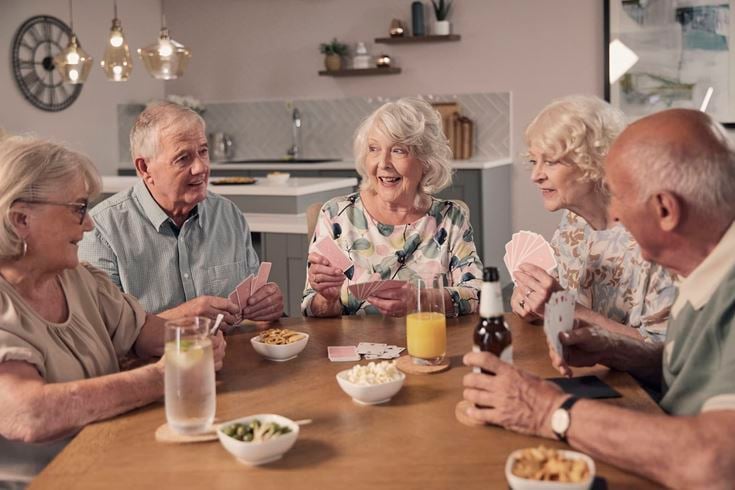 McCarthy & Stone homeowners socialise around a table playing cards