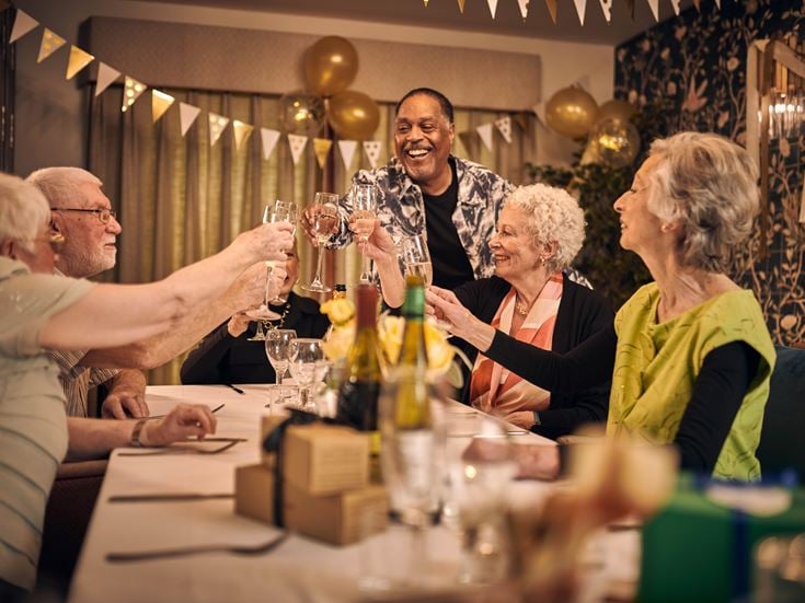A group of retirees gathered around a table, toasting in celebration. 