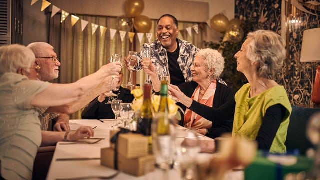 A group of retirees gathered around a table, toasting in celebration.