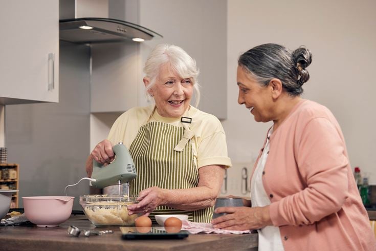 happy retirees cooking in their McCarthy & Stone senior living apartment.