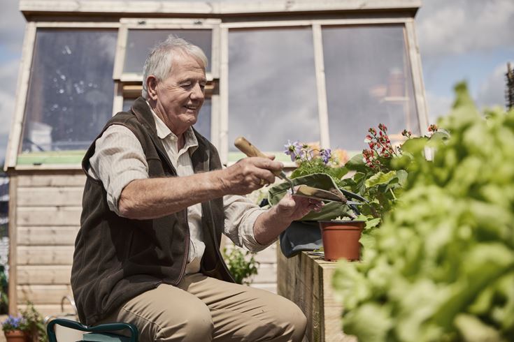a man sitting on a bench holding a plant