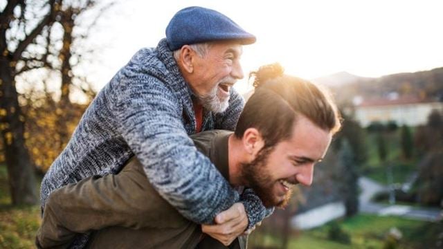 The history of fathers day illustrated by a son giving his older dad a piggy back.