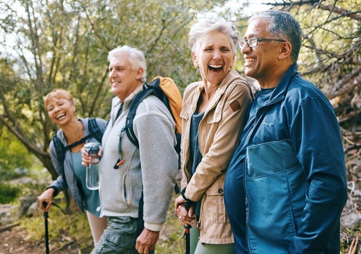 A group of four seniors, engrossed in conversation as they walk in nature
