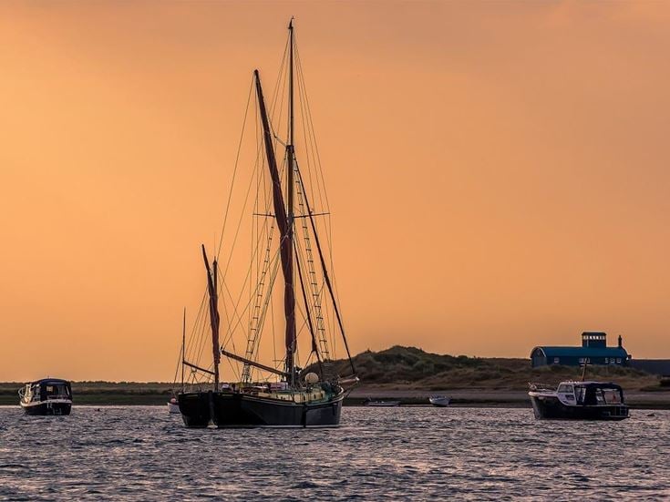 A view of boats moored at Blakeney Point, Norfolk looking towards the lifeboat station in the distance just before sunset