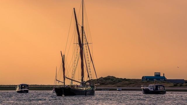 A view of boats moored at Blakeney Point, Norfolk looking towards the lifeboat station in the distance just before sunset