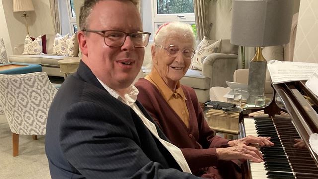 Homeowner Rosemary Chrimes and piano tutor Mikael Petersson playing the piano at Ryland Place Retirement Living PLUS development in Edgbaston