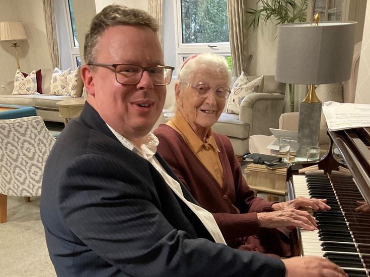 Homeowner Rosemary Chrimes and piano tutor Mikael Petersson playing the piano at Ryland Place Retirement Living PLUS development in Edgbaston
