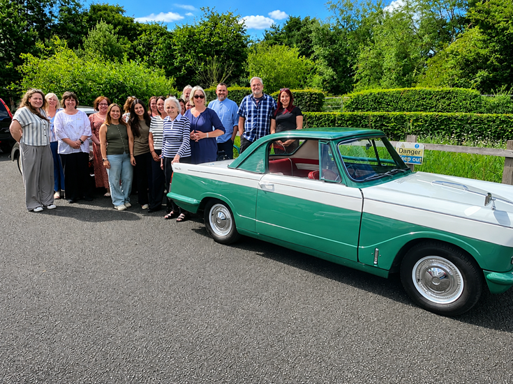 a group of people standing next to a green car