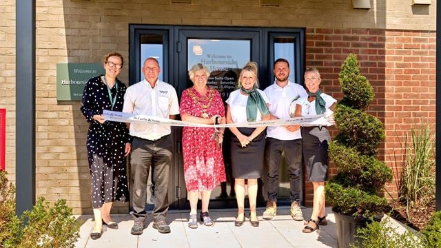 A group of McCarthy & Stone staff and the local Mayor cutting a ribbon in front of Harbourside House.