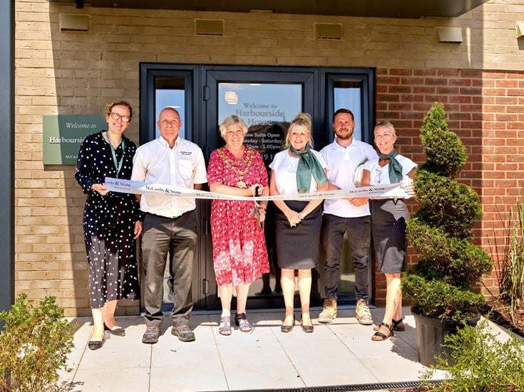 A group of McCarthy & Stone staff and the local Mayor cutting a ribbon in front of Harbourside House.