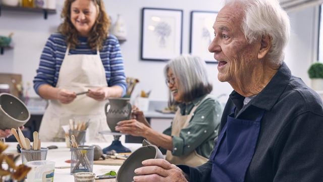 a group of people sitting at a table painting
