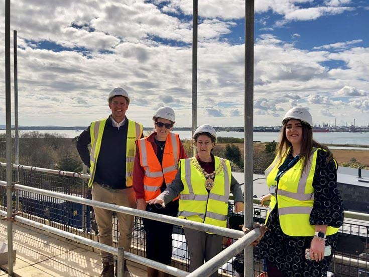 a group of people wearing safety vests and standing on a bridge