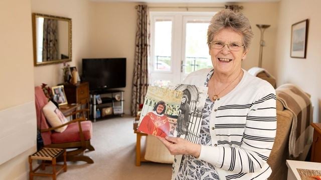 Elderton Place homeowner Gillian Harwood holding a picture of herself in her priestly attire