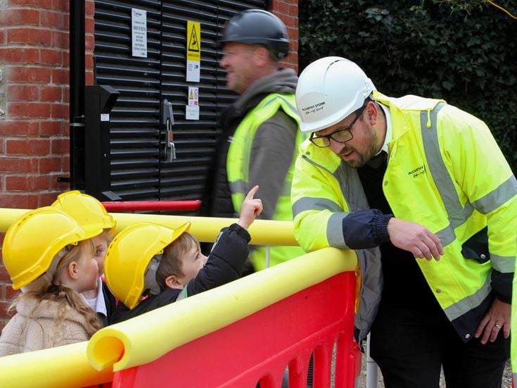 a group of people in safety vests looking at a person in a yellow vest