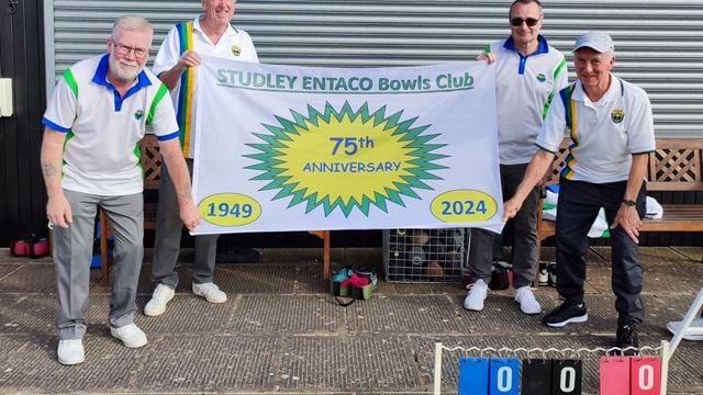 a group of men in matching t-shirts holding a banner