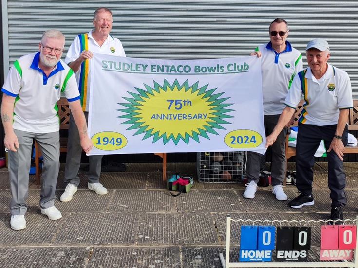a group of men in matching t-shirts holding a banner
