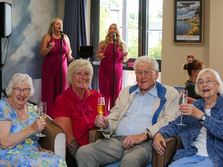 a group of people sitting on a couch holding wine glasses