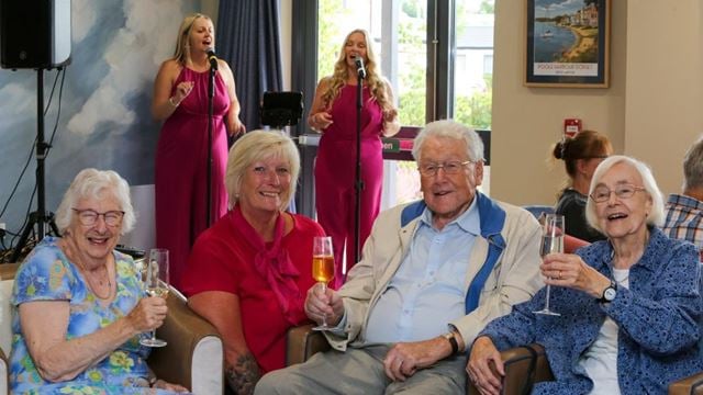 a group of people sitting on a couch holding wine glasses