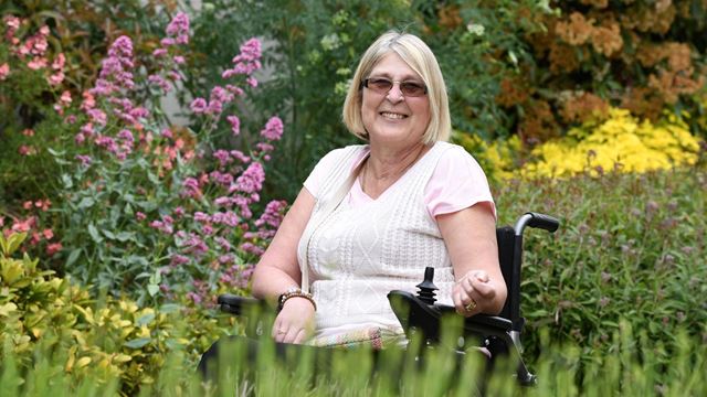 Veronica smiling, whilst sitting in a garden in bloom