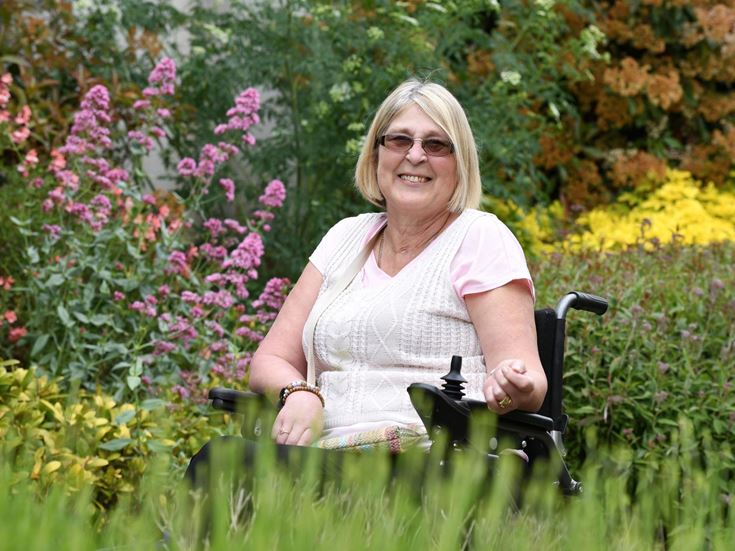 Veronica smiling, whilst sitting in a garden in bloom