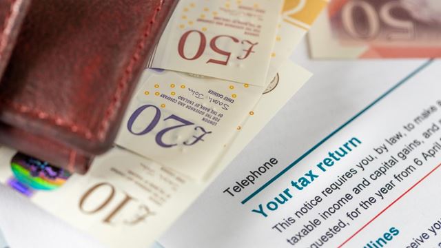 A wallet and British banknotes on top of a tax return letter.